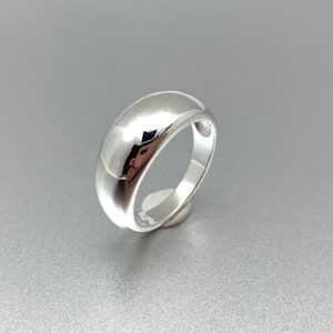May include: A silver ring with a rounded, smooth, and polished surface.
