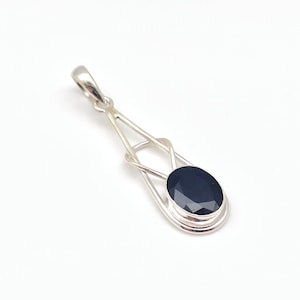 May include: A silver pendant with a dark blue oval gemstone set in a delicate, intricate design.