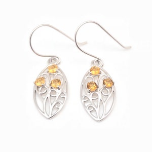 May include: A pair of silver earrings with a delicate leaf design and four small yellow gemstones.