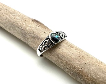 May include: A silver ring with an oval-shaped abalone shell inlay and intricate scrollwork design.