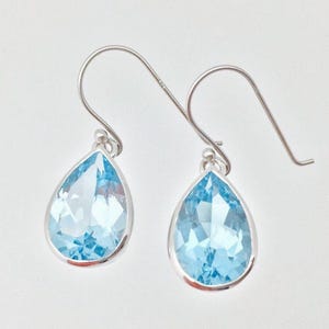 Puede incluir: Un par de pendientes de plata con piedras de topacio azul en forma de l&aacute;grima.