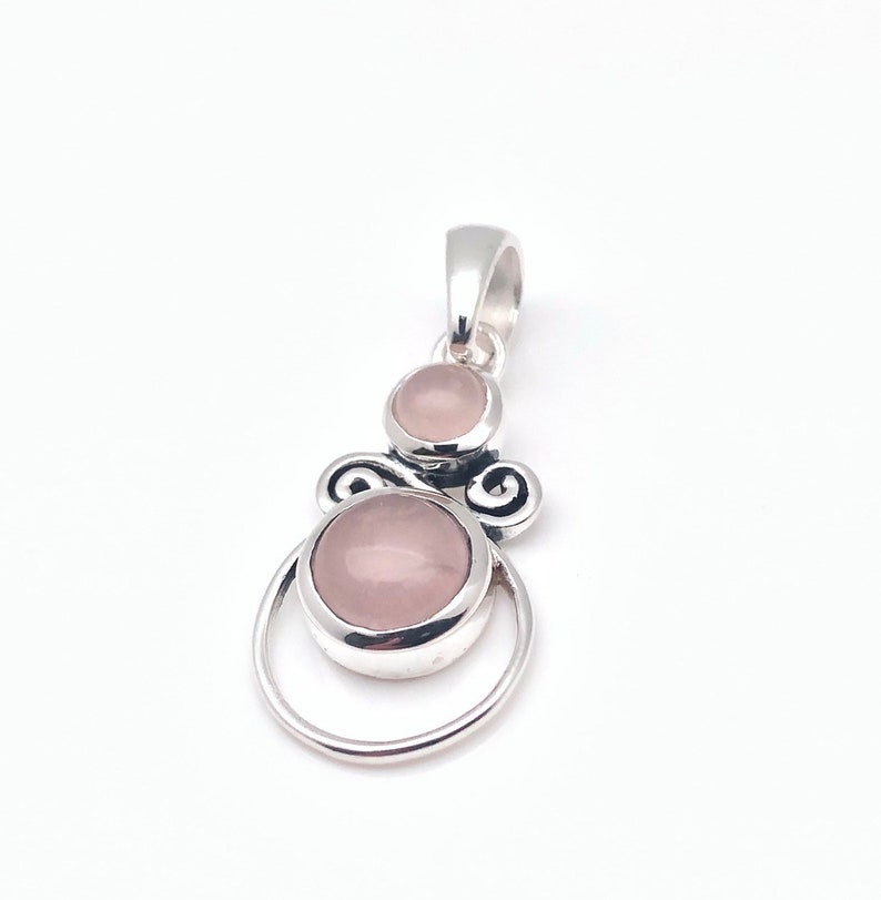 Peut inclure: Un pendentif en argent avec deux pierres de quartz rose. Le pendentif a un design d&eacute;licat et orn&eacute;.