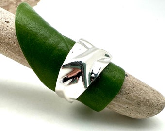 May include: A silver ring with a textured, wavy design. The ring is thick and has a wide band.