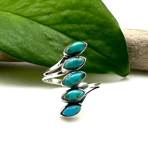 May include: A silver ring with five turquoise stones set in a curved design.
