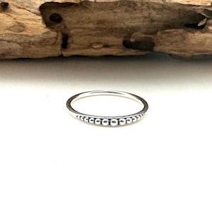 Peut inclure: Une bague en argent avec une rangée de petites perles autour de la bande.