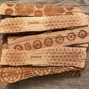 May include: A stack of wooden incense sticks with various designs, including a flower pattern, a geometric pattern, and the word "peace".