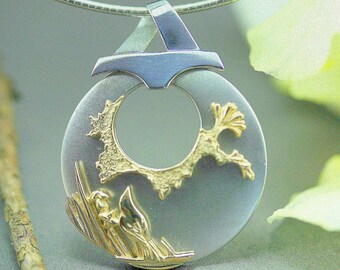 May include: A silver and gold pendant necklace. The pendant is a circular shape with a gold-colored, textured design on the front. The top of the pendant has a silver-colored, geometric design. The necklace chain is a thin, silver-colored metal.