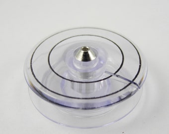 May include: Clear plastic bobbin with a black ring around the center. The bobbin has a small metal pin in the center.