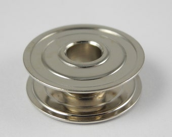 May include: A silver metal bobbin with a smooth, rounded surface and a central hole.