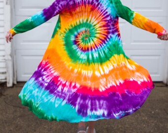 May include: A long-sleeved tie-dye cardigan in a vibrant spiral pattern. The colors include green, blue, purple, orange, and pink. The cardigan is open in the front and has long sleeves.