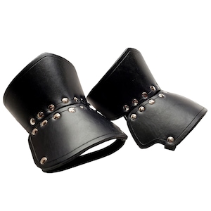 May include: A pair of black leather wrist cuffs with silver rivets. The cuffs have a flared design, possibly for costume or fashion. The leather is smooth and the rivets are evenly spaced, giving a decorative look.