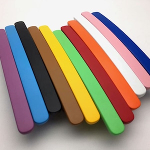 May include: A set of 14 colourful cabinet door pulls, each with a rounded edge. The pulls are arranged in a rainbow pattern, starting with purple and ending with blue.