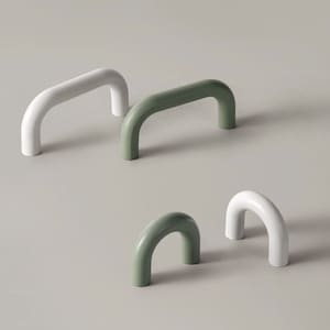 以下が含まれることがあります： 白と緑の異なるサイズのキャビネットプルが3つあります。プルはプラスチック製で、丸みを帯びたアーチ型の形状をしています。
