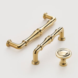 May include: Three gold-toned cabinet hardware pieces: a large and a small pull with a bamboo-inspired design, and a round knob.