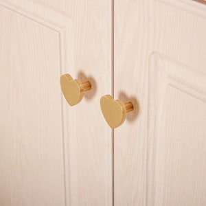May include: Two gold heart-shaped cabinet knobs with a brushed finish.
