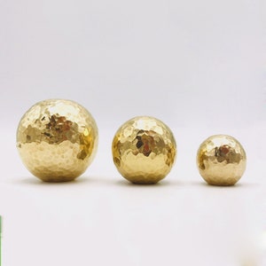May include: Three gold-coloured hammered metal knobs of different sizes.