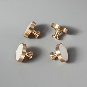 Può includere: Quattro pomelli rotondi in ottone per armadio con inserti in marmo bianco. I pomelli hanno un design semplice ed elegante e sarebbero un'ottima aggiunta a qualsiasi casa.
