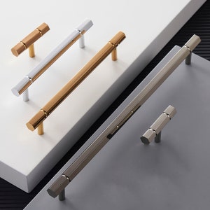 May include: Four different cabinet hardware pulls in various finishes. The pulls are made of metal and have a rectangular shape with rounded edges. The finishes include silver, gold, and brushed nickel.