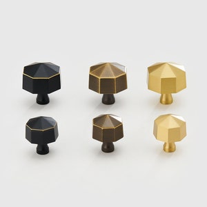 Pode incluir: Conjunto de seis botões para armário em três acabamentos: preto, latão antigo e latão polido. Cada botão tem uma forma geométrica octogonal.