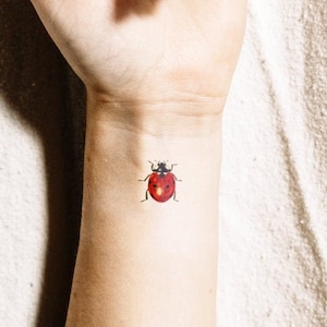 May include: A close-up of a person's wrist with a small red ladybug tattoo.