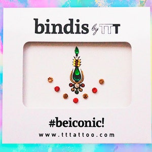 Puede incluir: Una tarjeta blanca con el texto "bindis by TTT" y el hashtag "#beiconic!" La tarjeta presenta un diseño de bindi con joyas verdes y doradas con acentos rojos y dorados.