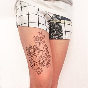 Può includere: Un disegno a linea nera di rose sulla gamba di una persona. Le rose sono disegnate in stile vintage con dettagli intricati.