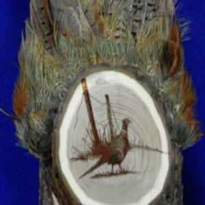 May include: A wooden plaque with a pheasant feather design and a woodburned image of a pheasant in the center.