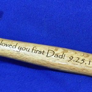 May include: A wooden handled hammer with a silver head. The handle is engraved with the text "Loved you first Dad! 9.25.15"