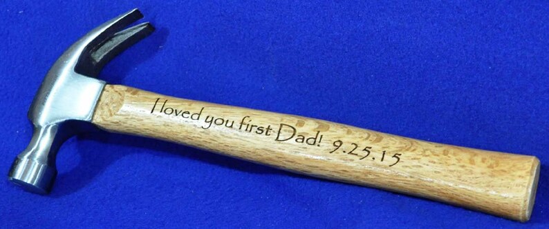 May include: A wooden handled hammer with a silver head. The handle is engraved with the text "Loved you first Dad! 9.25.15"