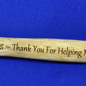 May include: A silver hammer with a wooden handle. The handle is engraved with the text "Pops - Thank You For Helping Me Build My Life".