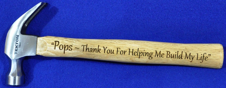 May include: A silver hammer with a wooden handle. The handle is engraved with the text "Pops - Thank You For Helping Me Build My Life".