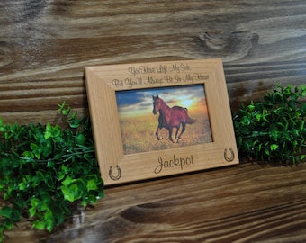 May include: A wooden picture frame with a horse photo inside. The frame has a horseshoe design and the text "You have left my side, but you'll always be in my heart. Jackpot".