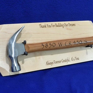 May include: A wooden plaque with a silver hammer mounted on it. The plaque has the text "Thank You For Building Our Dreams", "3850 W CR 450 S", and "Always Forever Grateful, Al & Tina" engraved on it.
