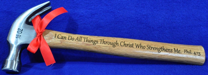 Peut inclure: Un marteau de 16 onces avec un manche en bois. Le manche est grav&eacute; du texte "Je peux tout faire par Christ qui me fortifie. Phil. 4:13". Un ruban rouge est nou&eacute; autour de la t&ecirc;te du marteau.