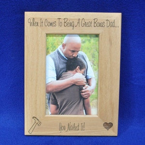 May include: A wooden picture frame with a photo of a man hugging a boy. The frame has the text "When it comes to being a great bonus dad... You nailed it!" and a hammer and heart design.
