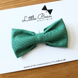 May include: A green bow tie with a small black diamond pattern, presented on a white card. The card features the text "Little Beau boutique" and the website address www.etsy.com/shop/littlebeaub.