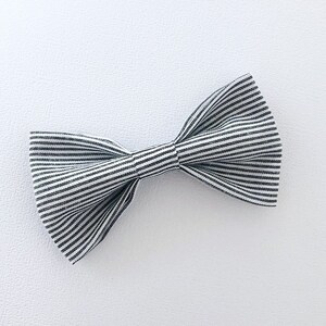 May include: A black and white striped bow tie. The bow tie is made of fabric and has a classic bow shape. The stripes are evenly spaced and run horizontally across the bow tie.