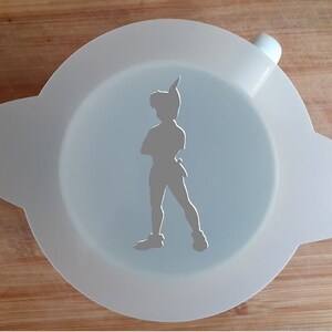 Puede incluir: Plantilla de plástico blanco con una silueta de Peter Pan, un personaje ficticio de la novela Peter Pan y Wendy de J.M. Barrie. La plantilla tiene dos asas a los lados.