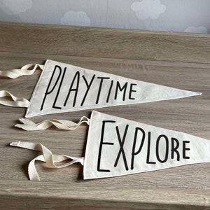 May include: Two white fabric pennants with black lettering. The top pennant says "PLAYTIME" and the bottom pennant says "EXPLORE".