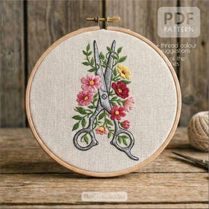 May include: An embroidered hoop with a floral design and scissors. The design features pink, red, and yellow flowers with green leaves, surrounding a pair of silver scissors. The text "PDF PATTERN" is visible.