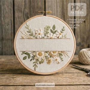 Może przedstawiać: Okrągła tamborkowa z kwiatowym wzorem. Wzór przedstawia białe i złote kwiaty z zielonymi liśćmi. Widoczny jest tekst "PDF PATTERN", a także "+ thread colour suggestions list of the stitches".