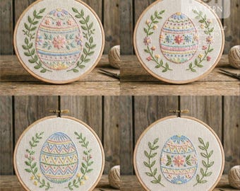 May include: Four embroidery hoops with Easter egg designs. Each egg is intricately stitched with colorful thread, featuring floral and geometric patterns. The eggs are surrounded by a green leaf wreath, set against a neutral fabric background, and framed in wooden hoops.