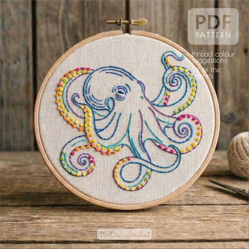 May include: Embroidered octopus design in a wooden hoop. The octopus is stitched with blue, teal, purple, and yellow thread. The text "PDF PATTERN" is in the upper right corner. The text "The Crafty Studio" is at the bottom.
