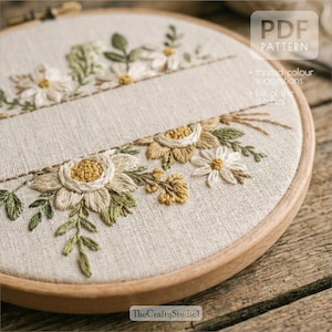 May include: Embroidered floral design in a wooden hoop. The design features cream and yellow flowers with green leaves and stems. The text "PDF PATTERN" is visible in the upper right corner. The text "TheCraftyStudio!" is visible in the lower left corner.