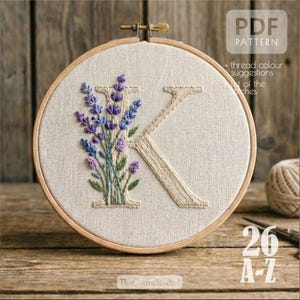 Puede incluir: Letra "K" bordada con flores de lavanda en un bastidor de madera. La lavanda es morada y azul, con hojas verdes. El fondo es de tela beige claro. El texto "PDF PATTERN" está en la esquina superior derecha.