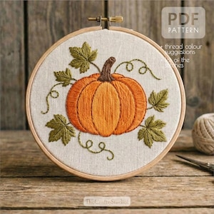 May include: Embroidered pumpkin in a wooden hoop. The pumpkin is orange with a brown stem, surrounded by green leaves and vines. The text "PDF PATTERN" is visible in the upper right corner. The text "The Crafty Studio!" is visible at the bottom.