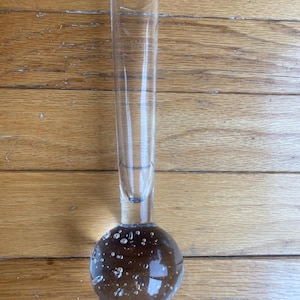 May include: A clear glass vase with a round, bubbled base and a tall, cylindrical neck.