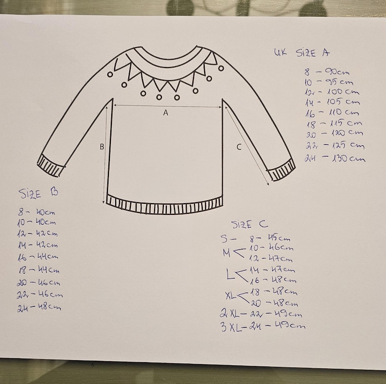 May include: A hand-drawn diagram of a sweater with measurements for different sizes labeled "UK Size A", "Size B", and "Size C". The diagram shows the length, width, and sleeve length of the sweater.