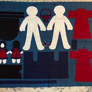 Op de afbeelding: Een blauw stoffen paneel met geprinte naaipatronen voor twee witte poppenfiguren, twee rode gewaden en twee kleine figuren met donker haar en rode jurken. De stof bevat instructieteksten en contouren voor het uitknippen van elk onderdeel.