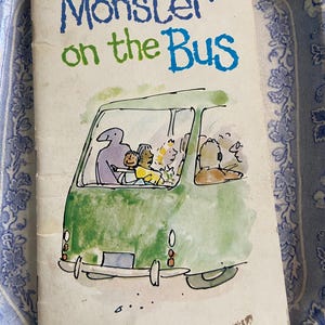 May include: A vintage children's book cover with a green bus and the title "Monster on the Bus" in blue and green lettering. The book is part of a series called "A Monster Book!!" by author "ralbounar".
